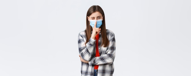 Coronavirus outbreak leisure on quarantine social distancing and emotions concept Attractive young woman in checked casual shirt and medical mask ask keep secret press finger to lips shush