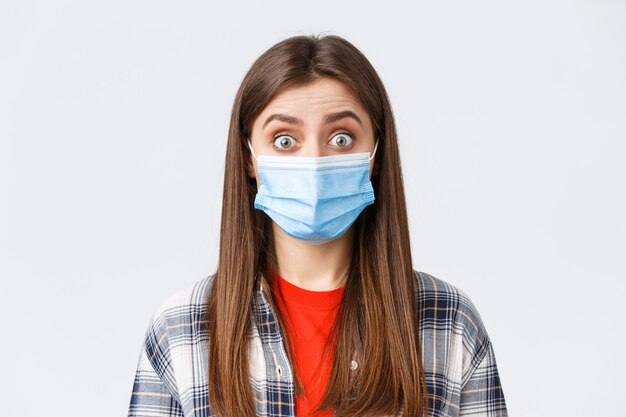 Coronavirus outbreak, leisure on quarantine, social distancing and emotions concept. Close-up of intrigued, surprised woman hear interesting news, wear medical mask, widen eyes