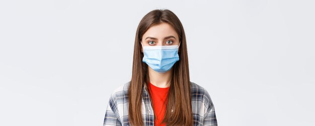 Coronavirus outbreak leisure on quarantine social distancing and emotions concept Closeup of young female student girl in medical mask looking at camera normal expression