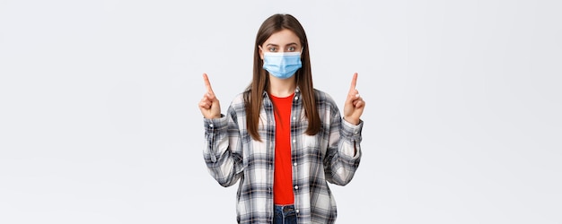 Coronavirus outbreak leisure on quarantine social distancing and emotions concept Confident and determined young woman selfisolating home pointing fingers up wear medical mask