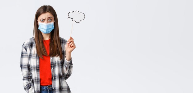 Free photo coronavirus outbreak leisure on quarantine social distancing and emotions concept confused and clueless young girl in medical mask have no ideas hold cloud stick near head