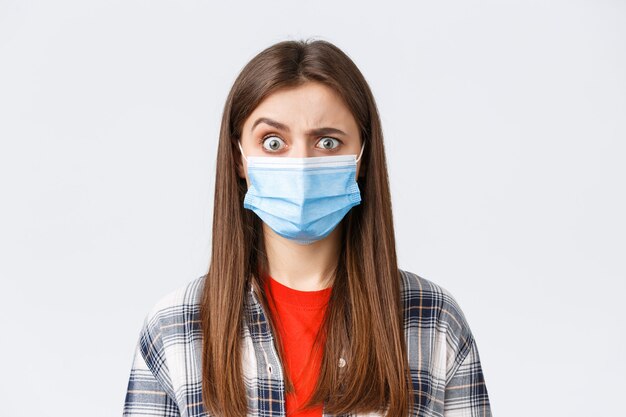 Coronavirus outbreak, leisure on quarantine, social distancing and emotions concept. Confused and startled girl in medical mask seeing something strange, raise eyebrow skeptical.