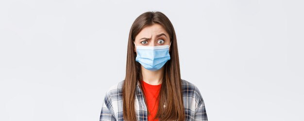 Coronavirus outbreak leisure on quarantine social distancing and emotions concept Confused young woman cant understand what happening look suspicious or surprised wear medical mask