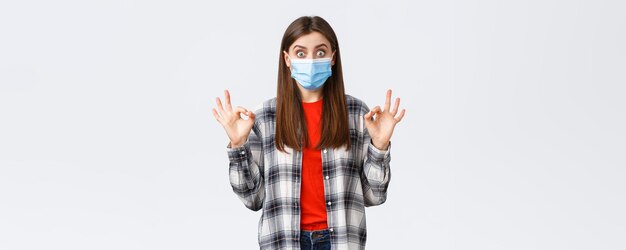 Coronavirus outbreak leisure on quarantine social distancing and emotions concept Excited and surprised young woman showing okay sign as see really good promo wear medical mask
