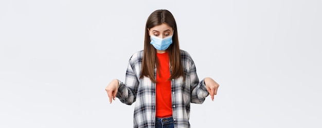 Foto gratuita tempo libero per l'epidemia di coronavirus in quarantena concetto di distanza sociale ed emozioni incuriosita ragazza carina in maschera medica donna che indossa dpi dall'infezione da virus che guarda verso il basso