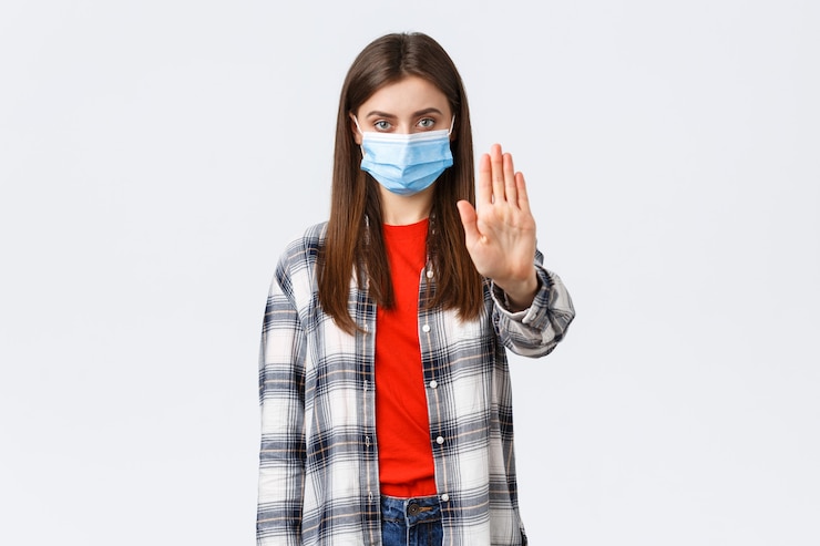 Free Photo coronavirus outbreak, leisure on quarantine, social distancing and emotions concept. stop spreading covid-19 stay home. serious young woman stretch hand in prohibition, restriction or warning