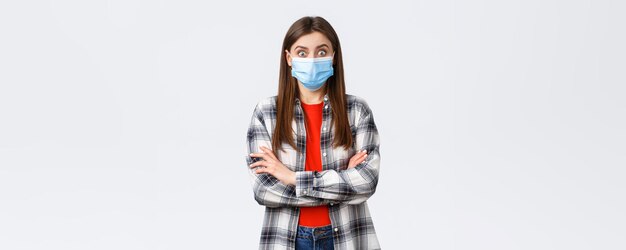 Coronavirus outbreak leisure on quarantine social distancing and emotions concept Surprised happy young female in medical mask and casual outfit widen eyes in amazement hear good news