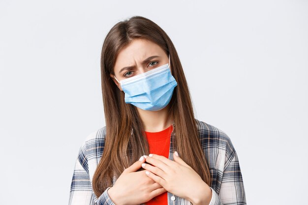 Coronavirus outbreak, leisure on quarantine, social distancing and emotions concept. Woman feeling fatigue while being sick, stay home covid-19, touch lungs, catching disease, wearing medical mask
