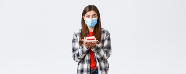 Coronavirus outbreak lifestyle during social distancing and holidays celebration concept Enthusiastic cute girl in medical mask holding delicious cake make home delivery from cafe