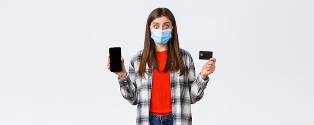 홈 온라인 쇼핑과 비접촉 결제 개념에서 일하는 코로나바이러스 발병 신용 카드와 휴대전화를 보여주는 의료 마스크를 쓴 흥분한 여성