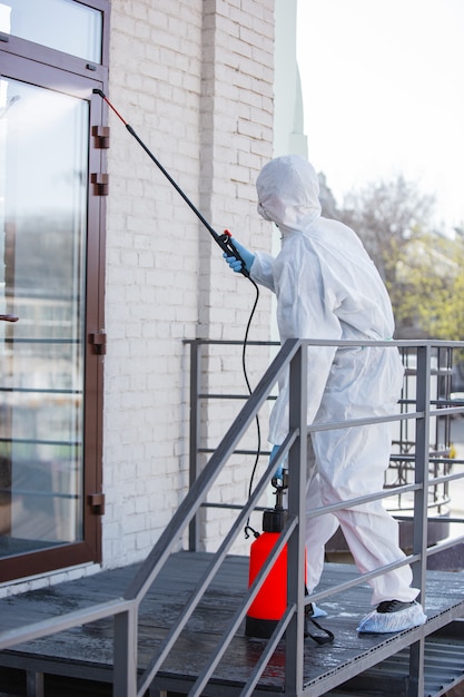 Coronavirus Pandemic. A disinfectant in a protective suit and mask sprays disinfectants in the room.