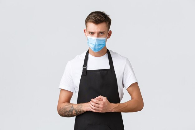 Coronavirus, social distancing in cafes and restaurants, business during pandemic concept. Serious and determined cafe manager listening to guest, wearing medical mask to prevent virus spread