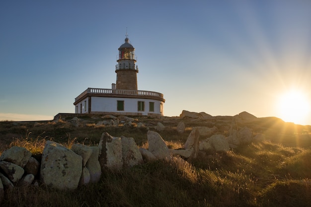 Corrubedo lighthouse surrounded by rocks and grass under the sunlight in Spain