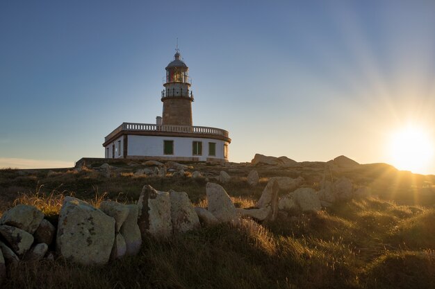 スペインの日光の下で岩や草に囲まれたコルベド灯台