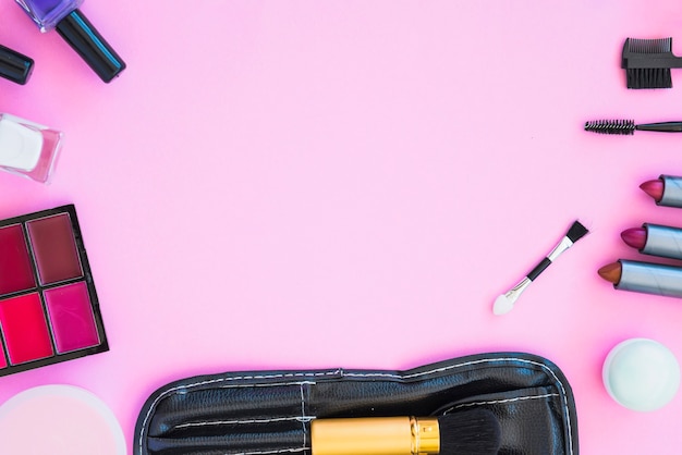 Cosmetic beauty products arranged on pink background with empty space for text