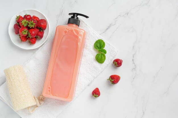 Cosmetic bottle strawberry shampoo on white surface