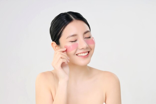 Cosmetic Eye Mask Close Up Beauty Face Asian Woman With Fresh Clean Skin Using Eye Pad Eye Care Treatment Isolated on white Beauty And Skin Care Concept