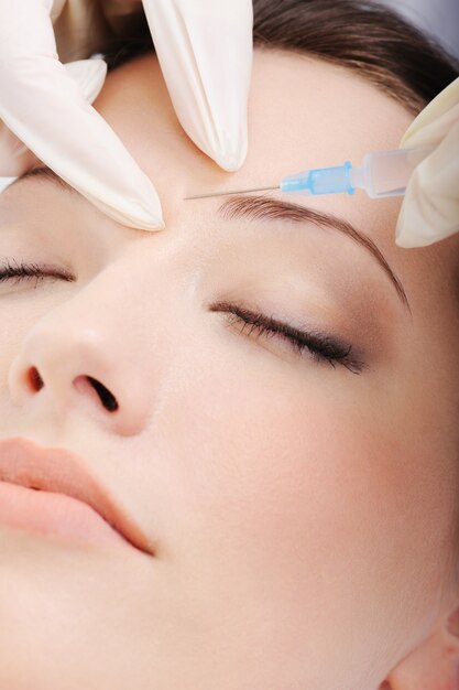 Cosmetic injection of botox to the pretty female face - close-up portrait