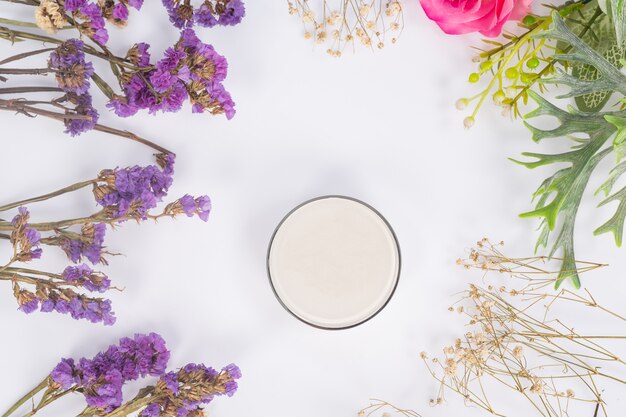 Cosmetic products and flowers on white