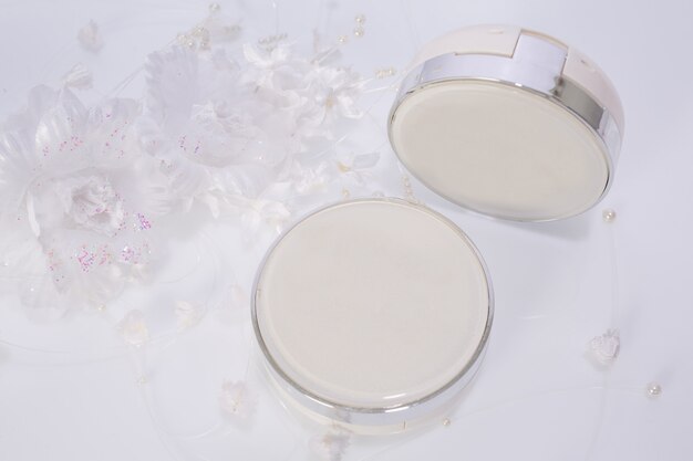 Cosmetic products and flowers on white