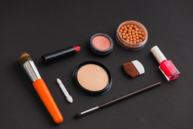 Косметические продукты и кисти для макияжа на черном фоне