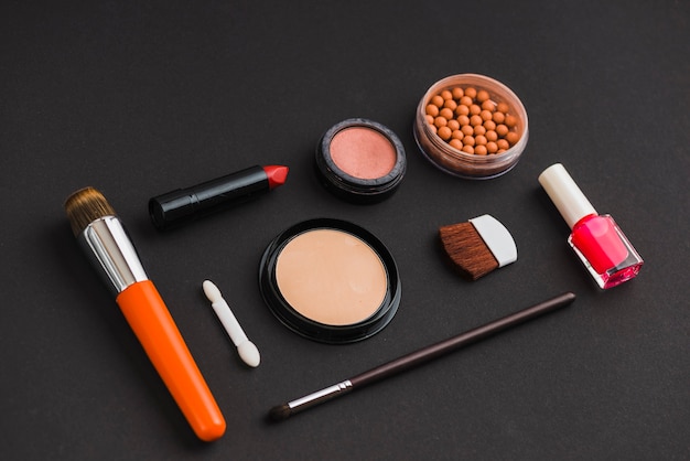 Cosmetic products and makeup brushes on black background