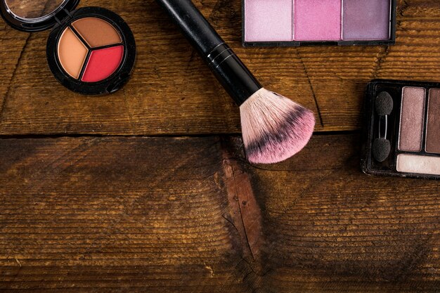 Cosmetic products with makeup brush on wooden background