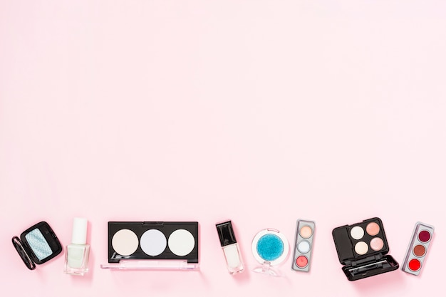 Cosmetics palette with nail polish bottles on pink background