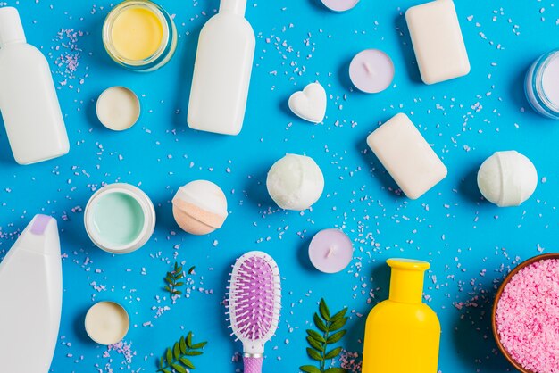 Cosmetics products and spread himalayan salt on blue background