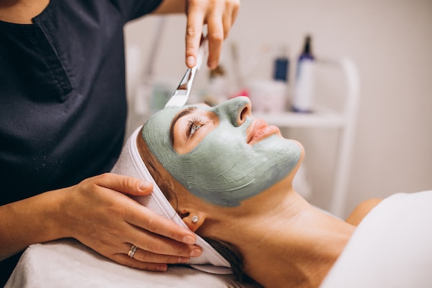 Cosmetologist applying mask on a face of client in a beauty salon