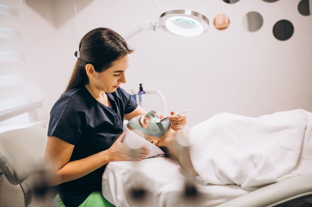 Cosmetologist applying mask on a face of client in a beauty salon