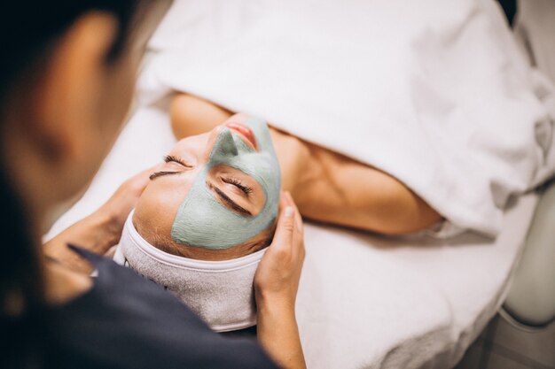 Cosmetologist applying mask on a face of client in a beauty salon