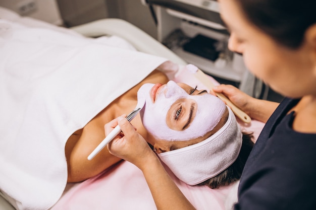 Cosmetologist applying mask on a face of client in a beauty salon