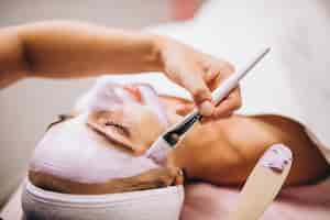 Free photo cosmetologist applying mask on a face of client in a beauty salon