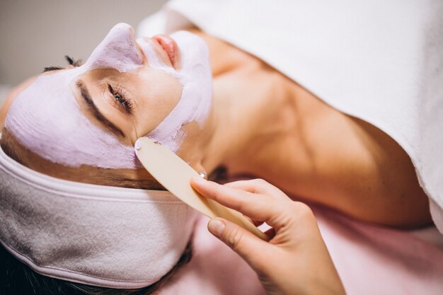 Cosmetologist applying mask on a face of client in a beauty salon