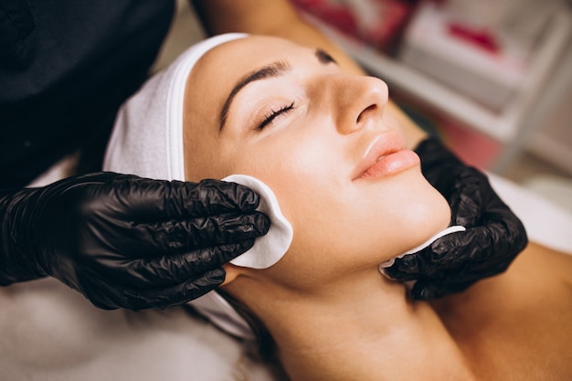 Cosmetologist cleaning face of a woman in a beauty salon