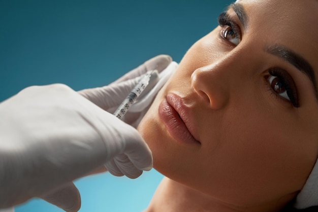 Free photo cosmetologist using syringe to correct female face