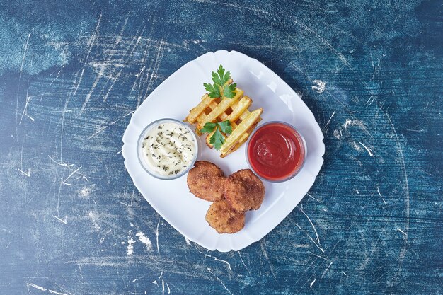 Cotlets and fried potatoes with herbs and sauces.