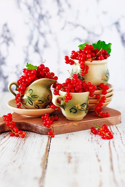 Cottage cheese cookie rolls with red currants on ceramic plate with vintage ceramic tea or coffee set, tea time, breakfast, summer sweets