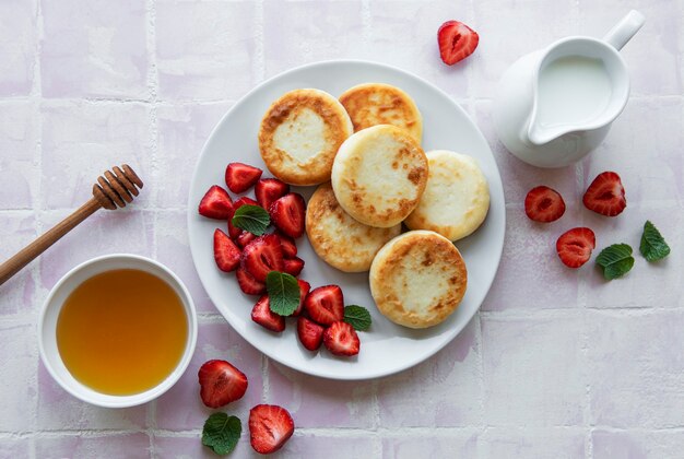 Cottage cheese pancakes ricotta fritters on ceramic plate with  fresh strawberry