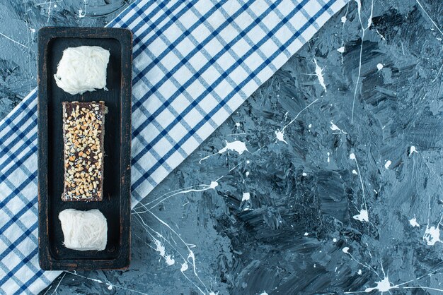 Cotton candies and chocolate waffle on a wooden plate on tea towel , on the blue table. 