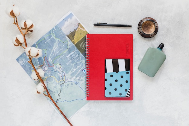 Cotton twig with map, notebook, and wallet on the background
