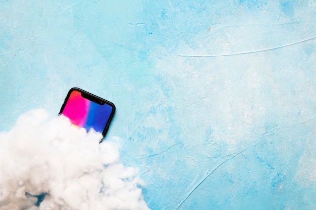 Cotton wool over mobile phone screen on painted blue background