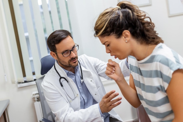 Coughing woman visiting doctor at clinic patient coughing at medical appointment with her doctor Sick woman visiting doctor at the hospital