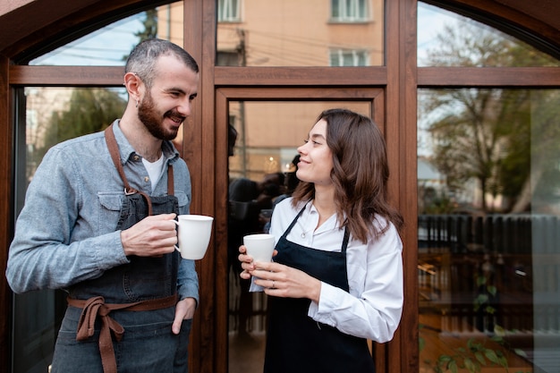 Couple in aprons enjoying coffee outside shop