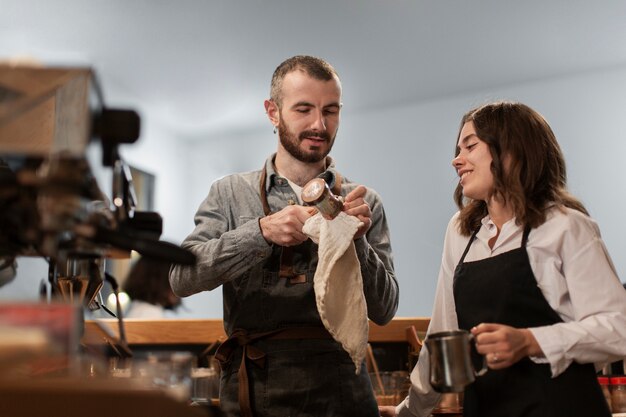 Couple in aprons holding coffee cups and talking