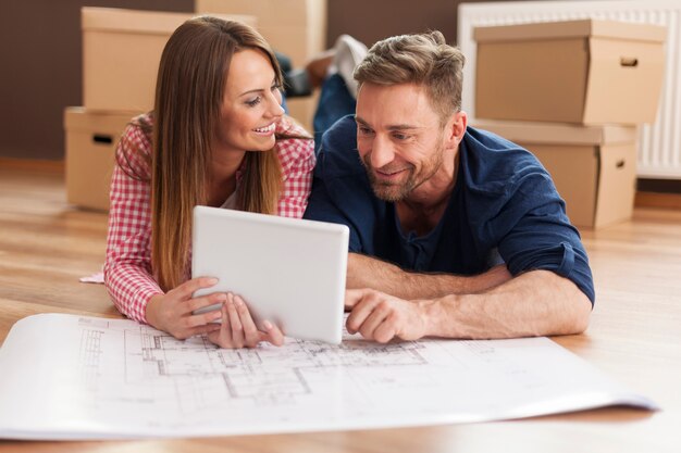 Couple arranging new apartment with digital tablet 
