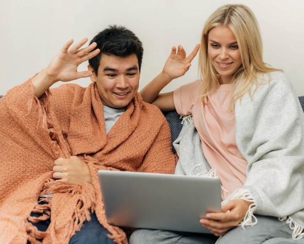 Бесплатное фото Пара дома вместе, используя ноутбук и размахивая