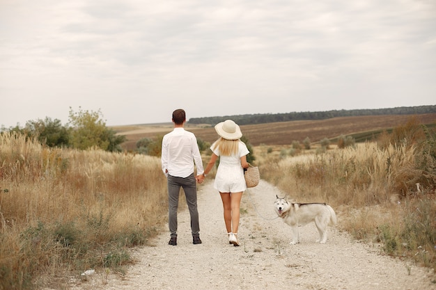 Couple in a autumn field playing with a dog