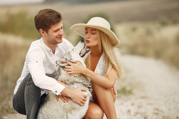 Free photo couple in a autumn field playing with a dog